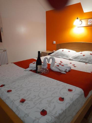 a bed with two swans towels and a bottle of champagne at Sobe i apartmani Kety in Kragujevac