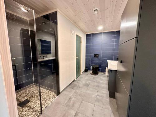 uma casa de banho com uma cabina de duche ao nível do chão e um lavatório. em Tors Cabin at Haukland Beach em Offersøya
