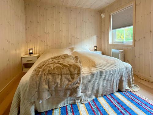 a bedroom with a bed with a blanket and a window at Tors Cabin at Haukland Beach in Offersøya