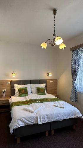 a bedroom with a large bed and a chandelier at Penzion u Fouska in Chodov