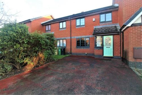 a red brick house with a green door at 2 Bed House - Sleeps 4 - Pets - Garden - Parking in Bolton