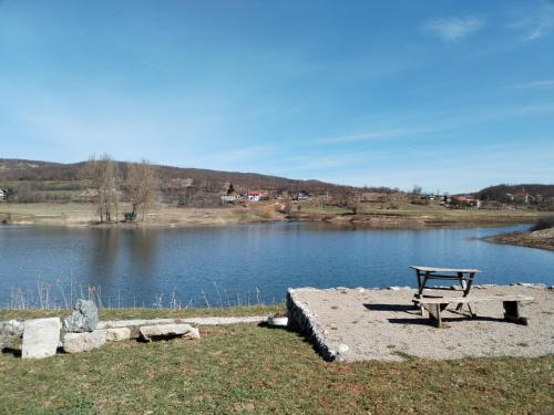 a picnic table sitting next to a lake at Studio Apartman Ivan in Otočac