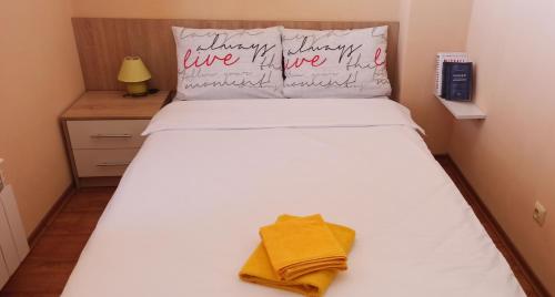 a bedroom with a white bed with a yellow towel on it at VV Apartment Bansko in Bansko