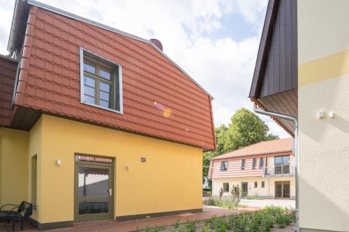 a building with a red roof and a building with yellow at Ferienwohnungen - barrierefrei - im sanierten Gutshof in Lalendorf