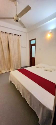 a bedroom with a red and white bed with a ceiling at Desire Village Rakwana in Rakwana