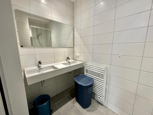 La salle de bains est pourvue d'un lavabo, d'un miroir et d'une poubelle. dans l'établissement Charming 1 bedroom serviced apartment 57m2, à Rotterdam
