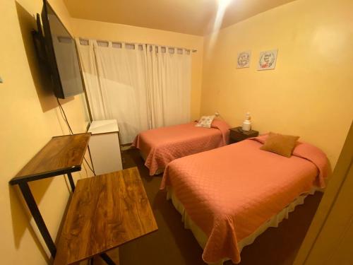 a room with two beds and a flat screen tv at Hospedaje Rios in Osorno