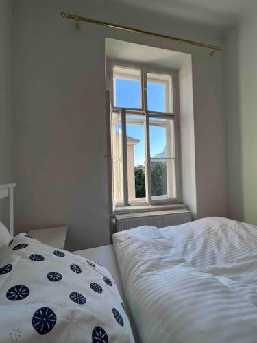 a white bedroom with a bed and a window at Altbauwohnung im Univiertel! in Graz