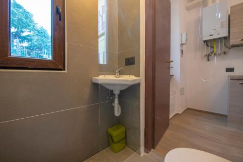 een badkamer met een wastafel, een toilet en een raam bij [CantikHouse] free wifi & smarTV in Verona