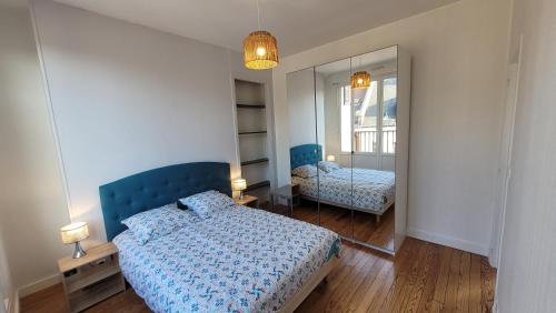 une chambre avec un lit bleu et un miroir dans l'établissement le balcon d'Amiens, à Amiens