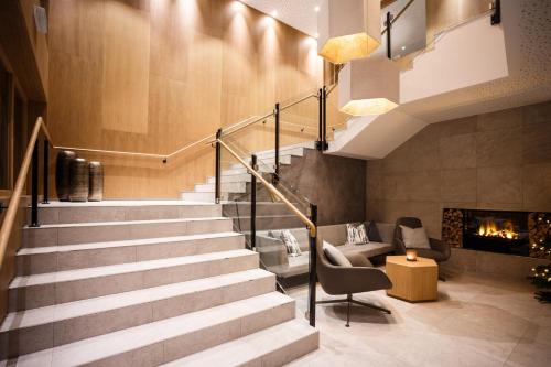 a staircase in a lobby with a fireplace at Das Hohe Salve Sportresort, 4 Sterne Superior in Hopfgarten im Brixental