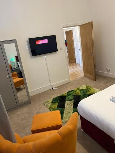 a room with a bed and a chair and a television at Spacious 2 Bedroom Apartment in Woolwich Arsenal in Woolwich