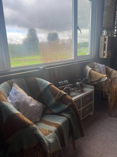 a living room with a couch and two windows at Bridie -rose with wood tub country retreat in Kington
