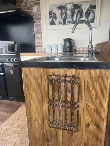 a kitchen sink with a faucet and a counter top at Bridie -rose with wood tub country retreat in Kington