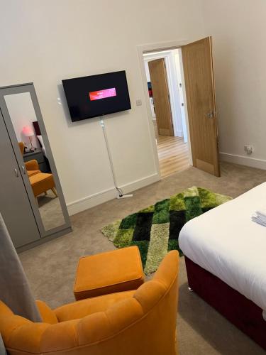 a room with a bed and a chair and a tv at Spacious 2 Bedroom Apartment in Woolwich Arsenal in Woolwich