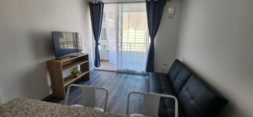 a living room with a couch and a television at Departamento Lynch Iquique in Iquique