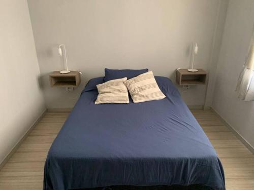 a bedroom with a blue bed with two pillows on it at Dpto. Rivadavia con vista al río in San Nicolás de los Arroyos