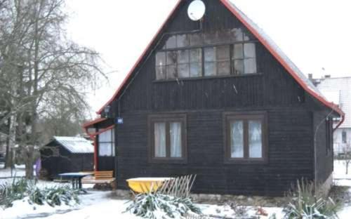 a black house with a red roof in the snow at Rekreační chata Hradištko in Hradišťko