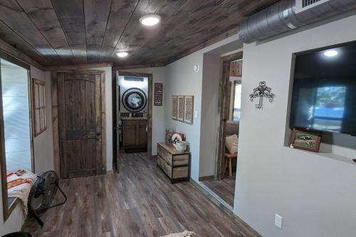 a living room with wooden floors and a tv on a wall at Enjoy Ozark History in Style! in Hasty