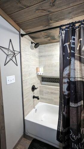 a bathroom with a bath tub and a shower curtain at Enjoy Ozark History in Style! in Hasty