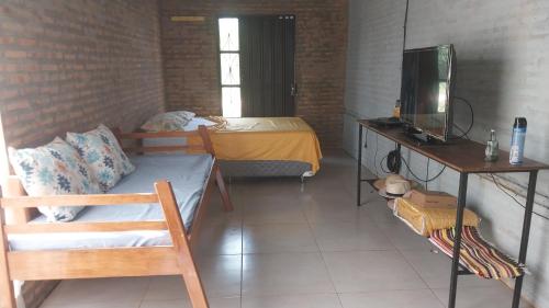 um pequeno quarto com uma cama e uma televisão em La casita del lago em Ypacarai