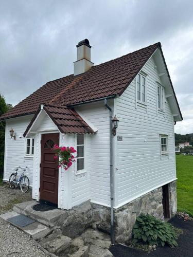 una pequeña casa blanca con una puerta roja en Hus med sentral beliggenhet en Tysvær