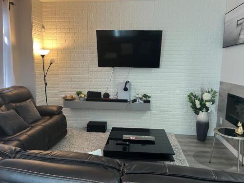 a living room with a couch and a tv on a wall at Home for yourself in Winnipeg