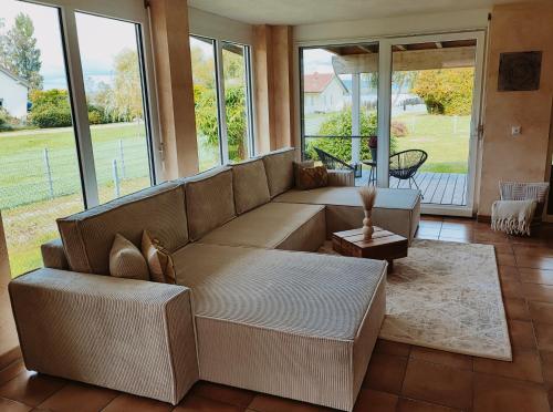 ein Wohnzimmer mit einem großen Sofa und Fenstern in der Unterkunft Wunderschönes Haus direkt am See - Seeblick, großer Garten, Südbalkon, Carport & Smart-TV in Gaienhofen