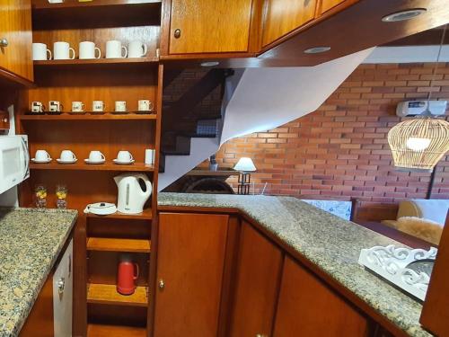 a kitchen with wooden cabinets and a counter top at Duplex estilo europeu Ednamar Apartamentos Bérgamo in Gramado