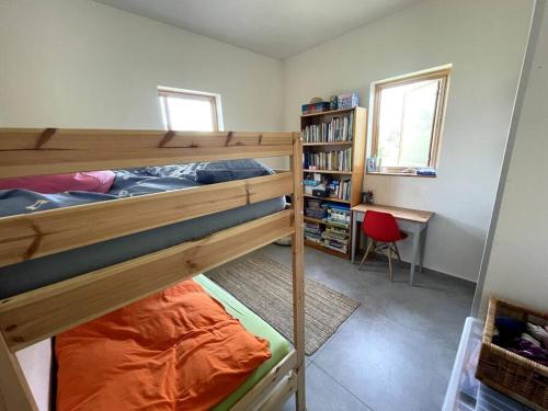 a bedroom with two bunk beds and a desk at Quiet cottage in the pastoral Galilee hills in Hararit