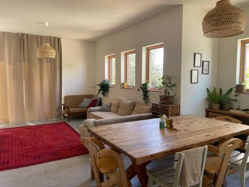 a living room with a wooden table and a couch at Quiet cottage in the pastoral Galilee hills in Hararit