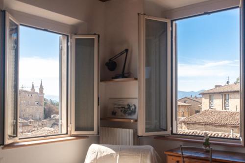 a bedroom with two windows with a view of a city at Il Cielo di Raffaello 2 in Urbino