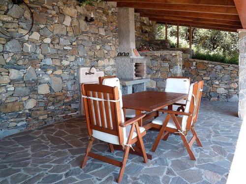 a wooden table and chairs on a patio with a stone wall at La Casetta in Corniglia