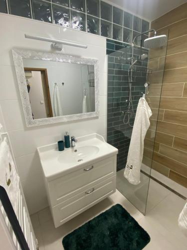 a bathroom with a sink and a shower and a mirror at Zeus apartmán in Rajecké Teplice