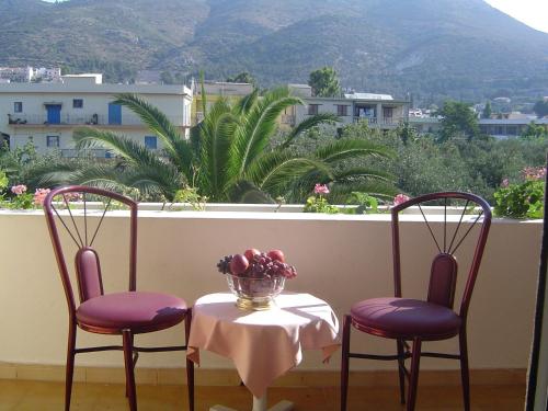 two chairs and a table with a bowl of fruit on a balcony at Paradise Hotel in Samos