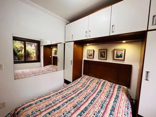 a bedroom with a bed and white cabinets at MRG Bavária 1D Próximo ao centro Gramado in Gramado
