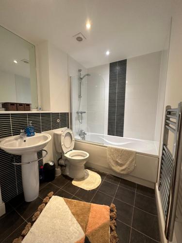 ein Badezimmer mit einer Badewanne, einem WC und einem Waschbecken in der Unterkunft Water Front APT Walk to the Beach & City Centre in Swansea
