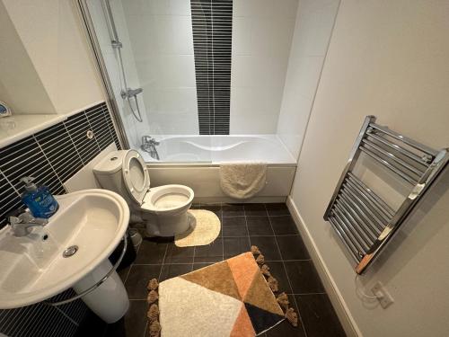 a bathroom with a sink and a toilet and a tub at Water Front APT Walk to the Beach & City Centre in Swansea