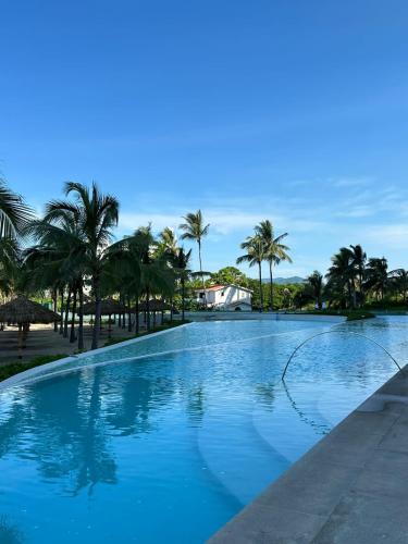 a large blue swimming pool with palm trees in the background at Maritima in Nuevo Vallarta