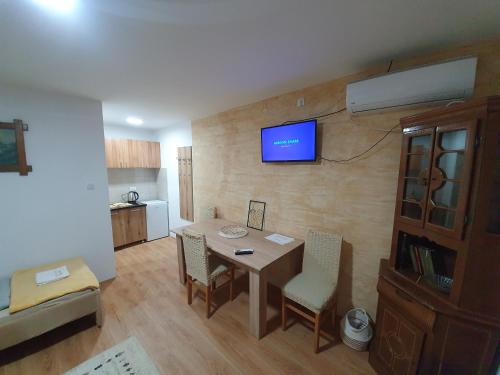 a living room with a table and a television on a wall at Zlatna Vila in Kanjiža
