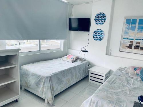 a white bedroom with two beds and a tv at Santa Catalina 404 in San Andrés