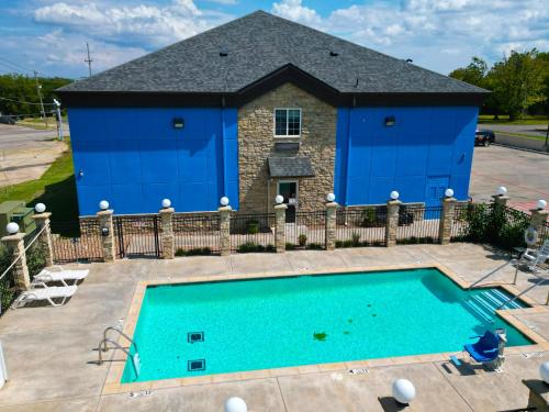 a pool in front of a house with a blue building at American Inn Madill in Madill