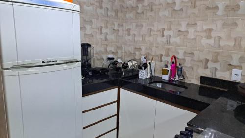 a kitchen with a white refrigerator and a sink at Casa nova e ventilada, varanda em Praia de Jacaraípe ES in Serra