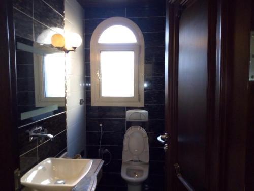 a bathroom with a toilet and a sink and a window at Heaven new Cairo in Cairo