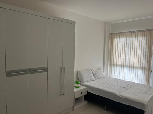 Apartamento Rio Marina Resort في مانغاراتيبا: غرفة نوم مع سرير وخزانة بيضاء