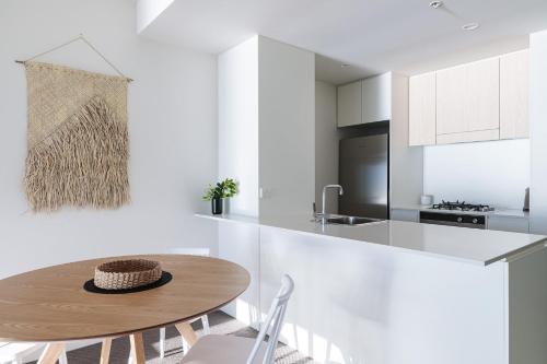 a white kitchen with a wooden table and chairs at The Calm in Newcastle
