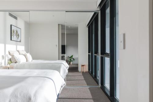 two beds in a room with white walls and mirrors at The Calm in Newcastle