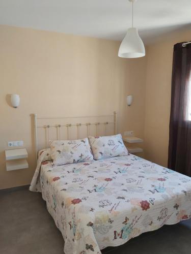 a bedroom with a bed with a floral comforter at Casa los Naranjos 1 in Conil de la Frontera