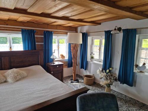 1 dormitorio con cortinas azules, 1 cama y 1 silla en Luxusní apartmán s krbem - Kunratické Švýcarsko, en Kunratice