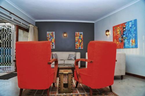 a living room with red chairs and a couch at Spacious Residence with Garden Close to Acacia Mall Kololo in Kampala